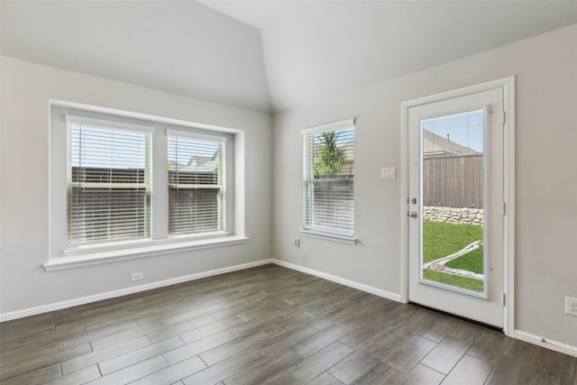 spare room featuring baseboards, vaulted ceiling, and dark wood finished floors