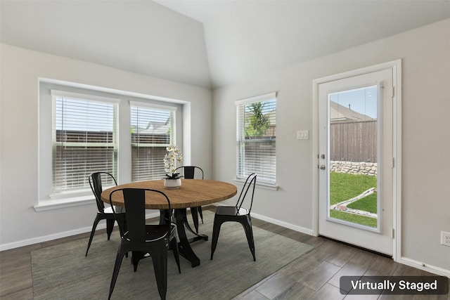 dining space featuring dark wood-style floors, vaulted ceiling, and baseboards
