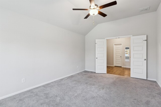 unfurnished bedroom with visible vents, vaulted ceiling, carpet floors, and baseboards