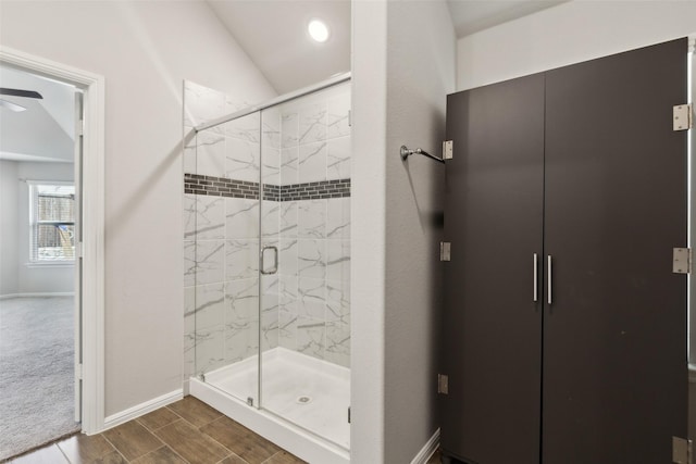 bathroom featuring vaulted ceiling, a marble finish shower, baseboards, a ceiling fan, and wood finish floors