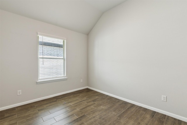 spare room featuring vaulted ceiling, dark wood-style floors, and baseboards