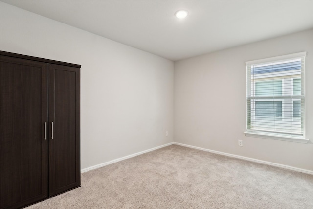 unfurnished bedroom with light colored carpet and baseboards
