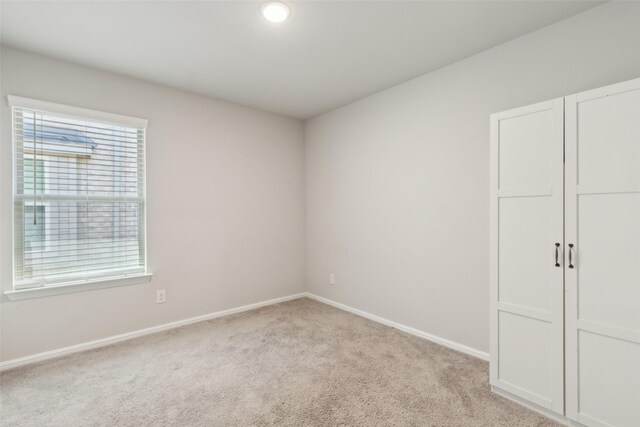 unfurnished bedroom with multiple windows, light carpet, and baseboards