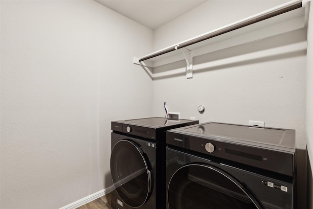washroom featuring separate washer and dryer, wood finished floors, laundry area, and baseboards
