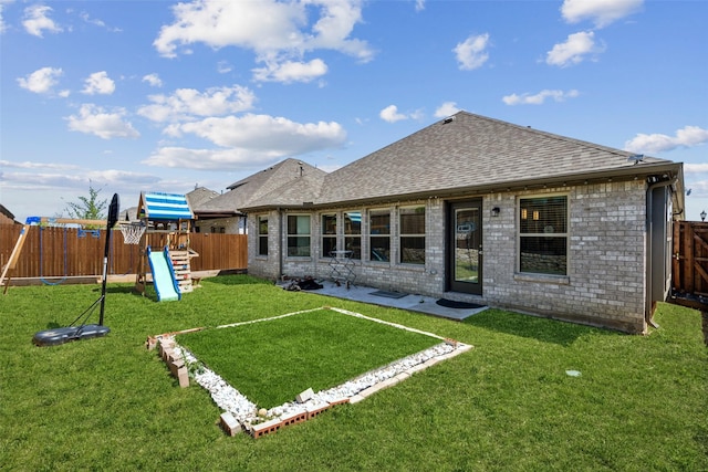 rear view of property featuring a yard, a playground, a fenced backyard, and roof with shingles