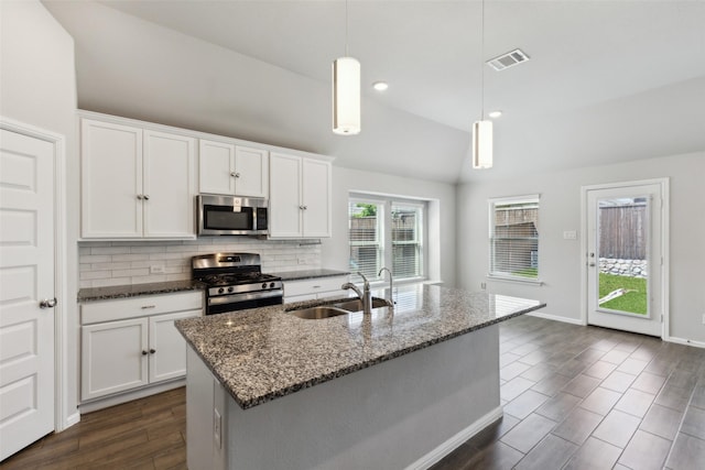 kitchen featuring a sink, decorative backsplash, visible vents, vaulted ceiling, and appliances with stainless steel finishes