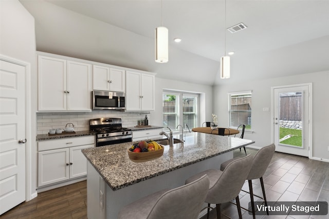 kitchen with lofted ceiling, a kitchen breakfast bar, a sink, visible vents, and stainless steel appliances