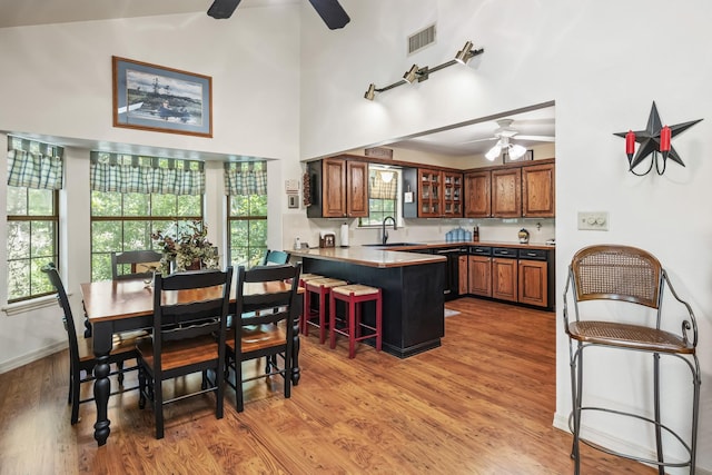 kitchen featuring brown cabinets, a peninsula, a ceiling fan, and a sink