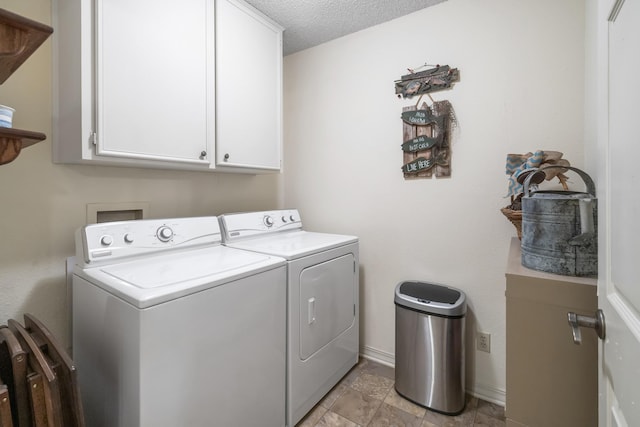 laundry room featuring a textured ceiling, washing machine and clothes dryer, cabinet space, and baseboards