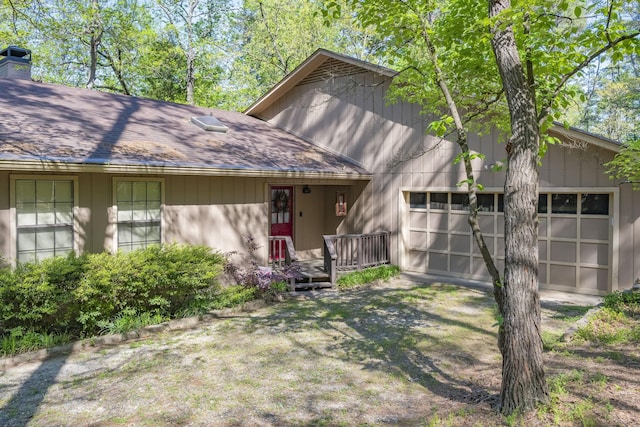back of house featuring a garage, a shingled roof, and a chimney