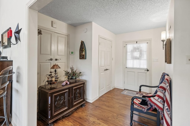entryway with baseboards, wood finished floors, and a textured ceiling
