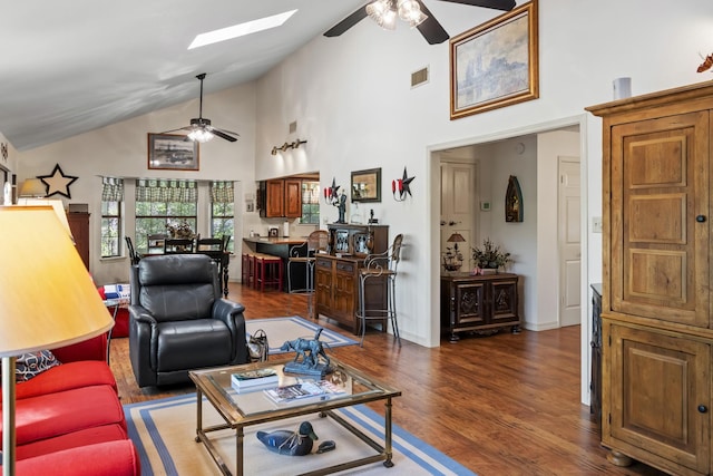 living area with dark wood-style flooring, ceiling fan, high vaulted ceiling, visible vents, and a skylight