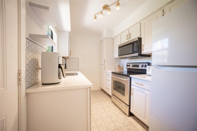 kitchen with a sink, stainless steel appliances, tasteful backsplash, light countertops, and white cabinets
