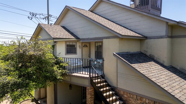 exterior space with stucco siding and roof with shingles