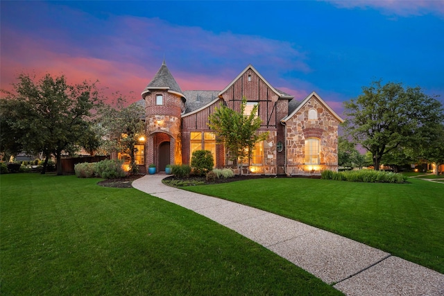 french country style house featuring brick siding, a front lawn, and stone siding