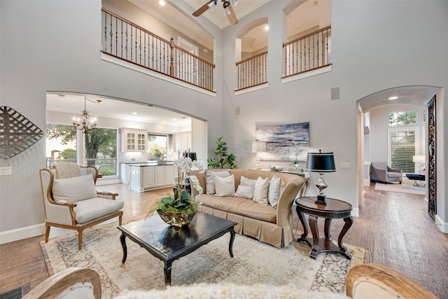 living room with baseboards, arched walkways, ornamental molding, and light wood finished floors