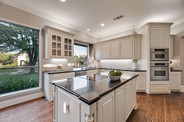 kitchen with a sink, dark wood-type flooring, visible vents, and plenty of natural light