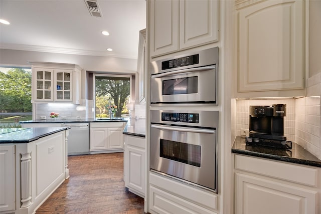 kitchen featuring recessed lighting, glass insert cabinets, appliances with stainless steel finishes, ornamental molding, and backsplash