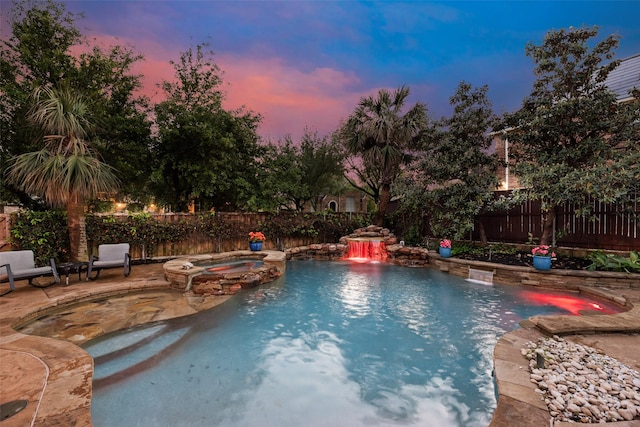 pool at dusk with a pool with connected hot tub, a patio, and a fenced backyard