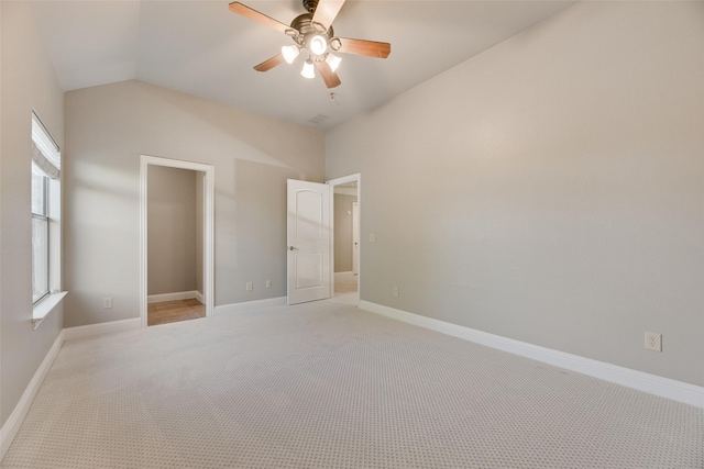 unfurnished bedroom featuring baseboards, ceiling fan, light colored carpet, and lofted ceiling