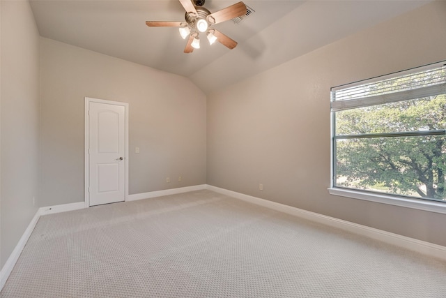 empty room with a ceiling fan, lofted ceiling, light colored carpet, and baseboards
