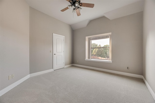 spare room with ceiling fan, vaulted ceiling, light carpet, and baseboards