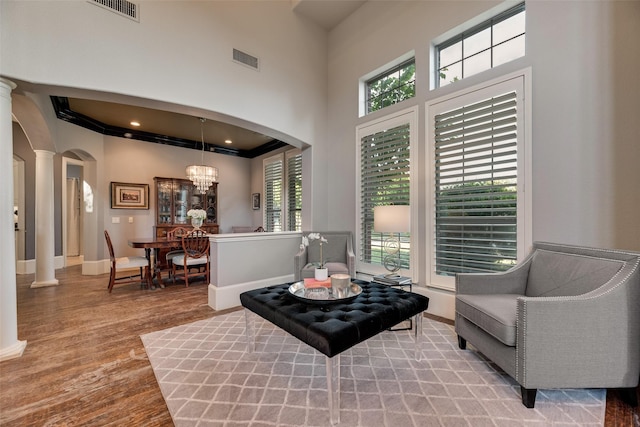 sitting room with decorative columns, wood finished floors, visible vents, and arched walkways