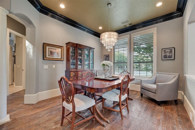 dining space with baseboards, ornamental molding, an inviting chandelier, and wood finished floors