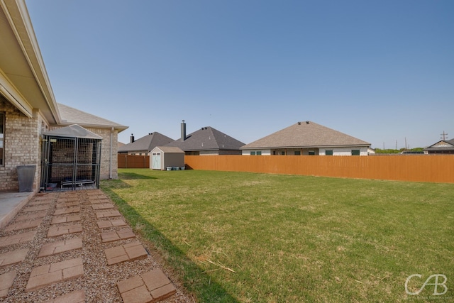view of yard with an outbuilding, a storage unit, and a fenced backyard