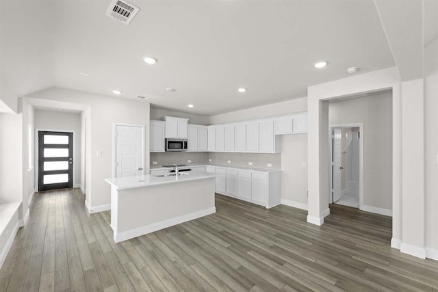 1640 Meadow Crst, Aubrey, TX 76227 - kitchen featuring stainless steel microwave, wood finished floors, white cabinets, an island with sink, and light countertops