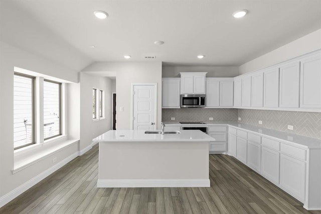 1640 Meadow Crst, Aubrey, TX 76227 - kitchen with stainless steel microwave, a sink, an island with sink, tasteful backsplash, and wood finished floors