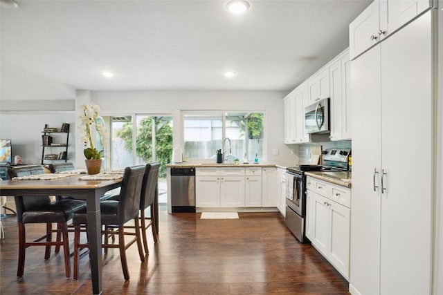 kitchen featuring recessed lighting, appliances with stainless steel finishes, a sink, white cabinetry, and dark wood-type flooring