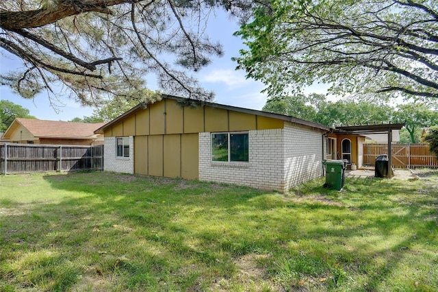 rear view of house with brick siding, board and batten siding, a fenced backyard, and a lawn
