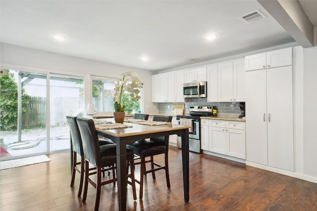 kitchen with stainless steel appliances, dark wood-type flooring, visible vents, backsplash, and white cabinets