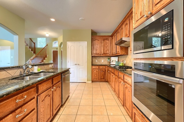 13579 Hemlock Trl, Frisco, TX 75035 - kitchen featuring a sink, stainless steel appliances, brown cabinets, decorative backsplash, and light tile patterned floors