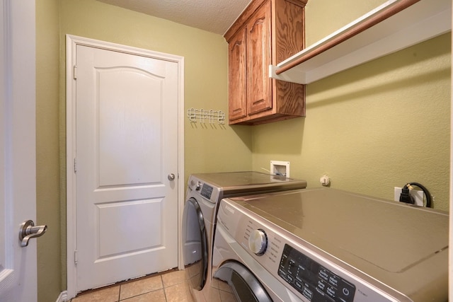 laundry area with light tile patterned floors, washing machine and clothes dryer, cabinet space, and a textured ceiling
