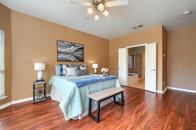 bedroom with connected bathroom, visible vents, ceiling fan, baseboards, and wood finished floors