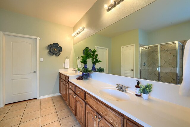 bathroom with tile patterned floors, a shower stall, double vanity, and a sink