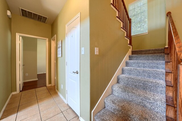 staircase featuring baseboards, visible vents, and tile patterned flooring