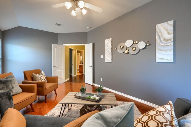living area featuring visible vents, ceiling fan, baseboards, vaulted ceiling, and wood finished floors
