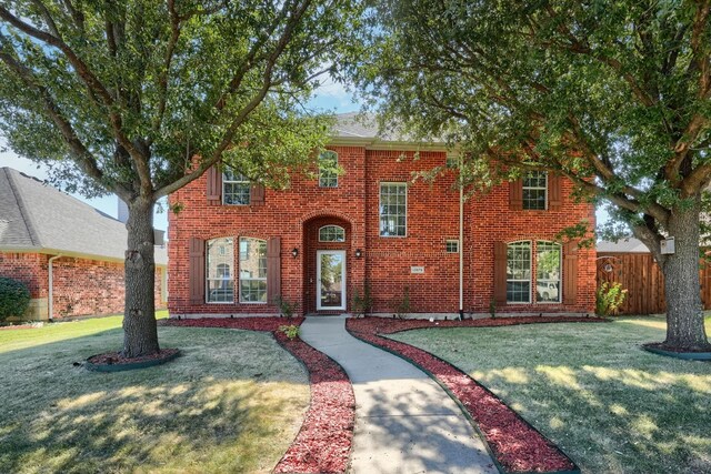 view of front facade featuring fence, a front yard, and brick siding