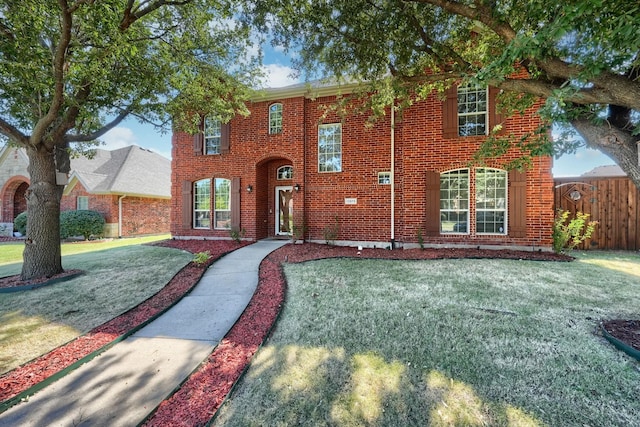 view of front of house featuring brick siding, fence, and a front yard
