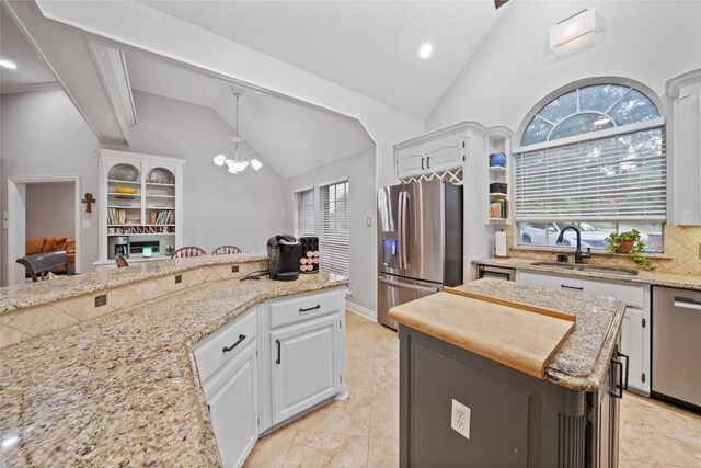 kitchen with hanging light fixtures, a chandelier, stainless steel appliances, white cabinets, and a sink