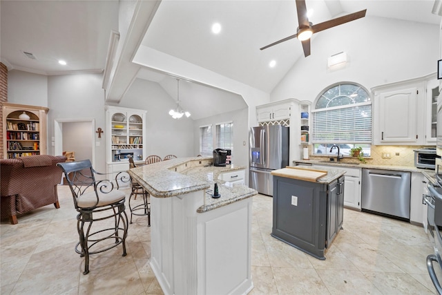 kitchen with a kitchen island with sink, a kitchen bar, high vaulted ceiling, and stainless steel appliances
