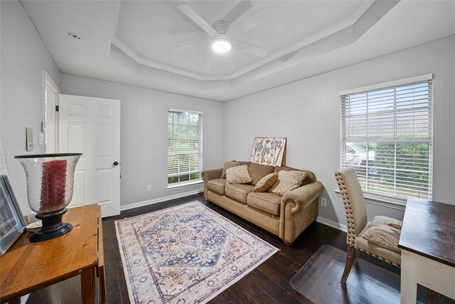 living room with dark wood-style floors, ceiling fan, a raised ceiling, and baseboards