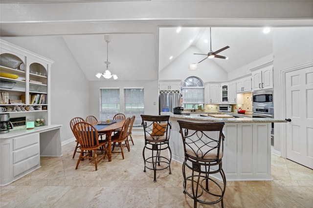 kitchen featuring glass insert cabinets, a toaster, appliances with stainless steel finishes, vaulted ceiling, and a kitchen bar