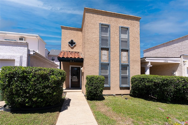 view of front facade with stucco siding and a front lawn