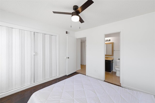 bedroom featuring a closet, ceiling fan, ensuite bathroom, baseboards, and visible vents