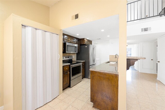 kitchen featuring appliances with stainless steel finishes, light tile patterned flooring, visible vents, and a sink