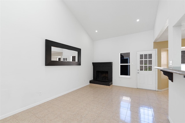 unfurnished living room featuring baseboards, light tile patterned flooring, recessed lighting, a fireplace, and high vaulted ceiling